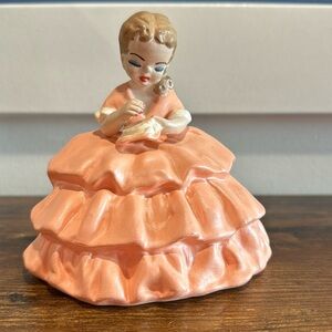 Handcrafted generic Josef ceramic girl cross stitching on a stool